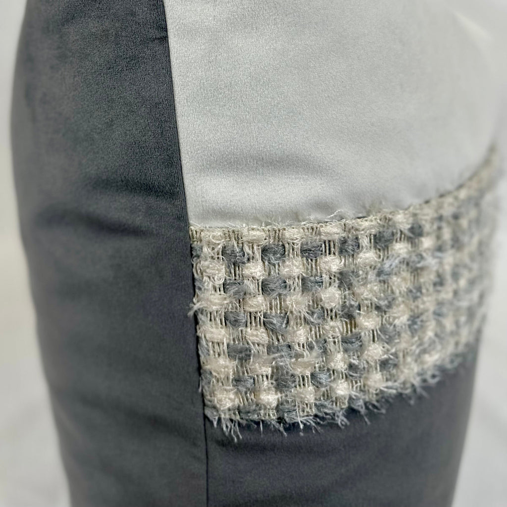 Close-up of a gray upholstered chair or cushion with a wide woven tweed band in gray, white, and beige tones around the seat.