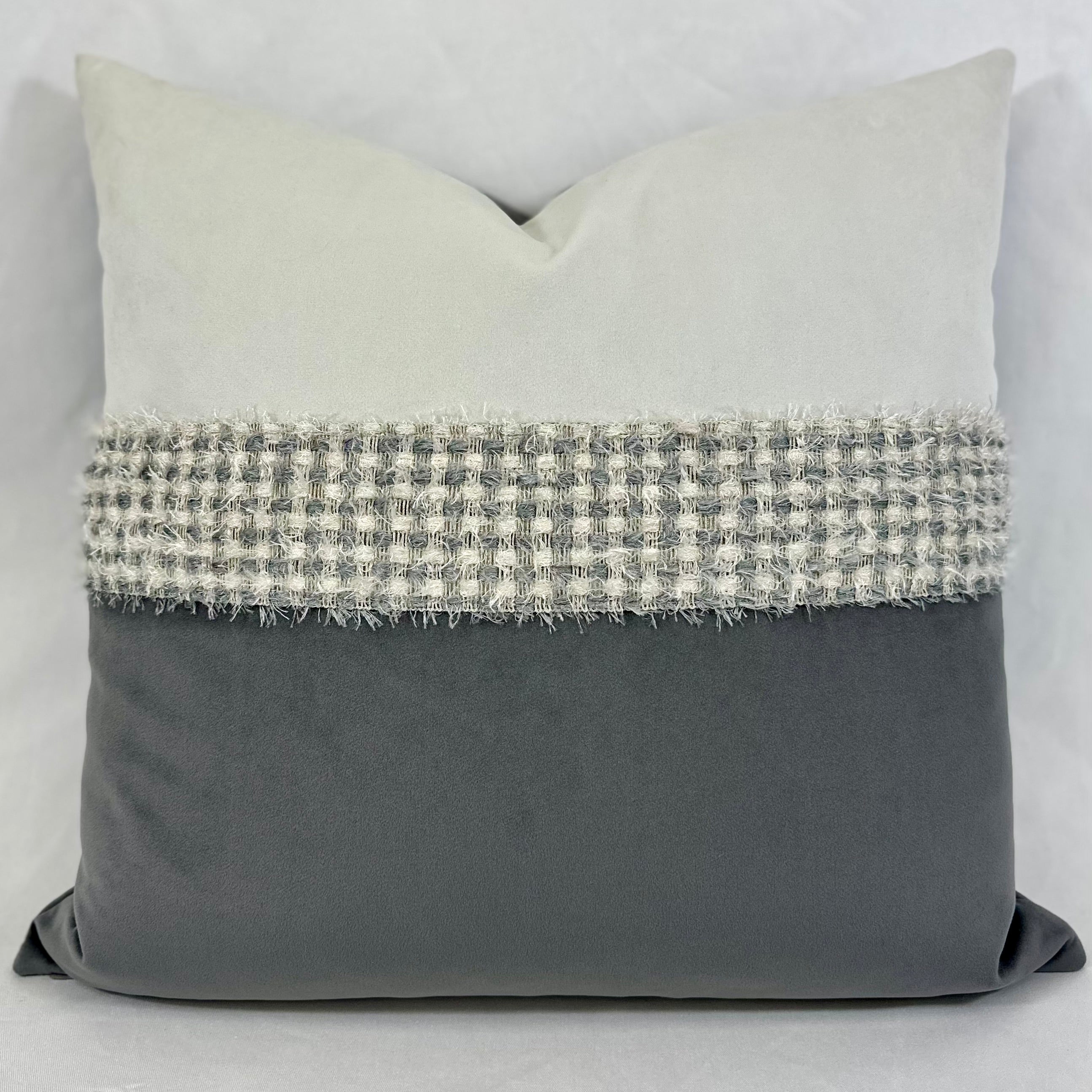 A square decorative throw pillow with a color-blocked design, featuring a light gray top section, a textured gray and white woven band across the middle, and a solid dark gray bottom section.