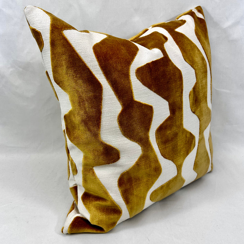 A square throw pillow featuring a bold, wavy chevron pattern in mustard yellow velvet and off-white textured fabric, set against a neutral light gray background.