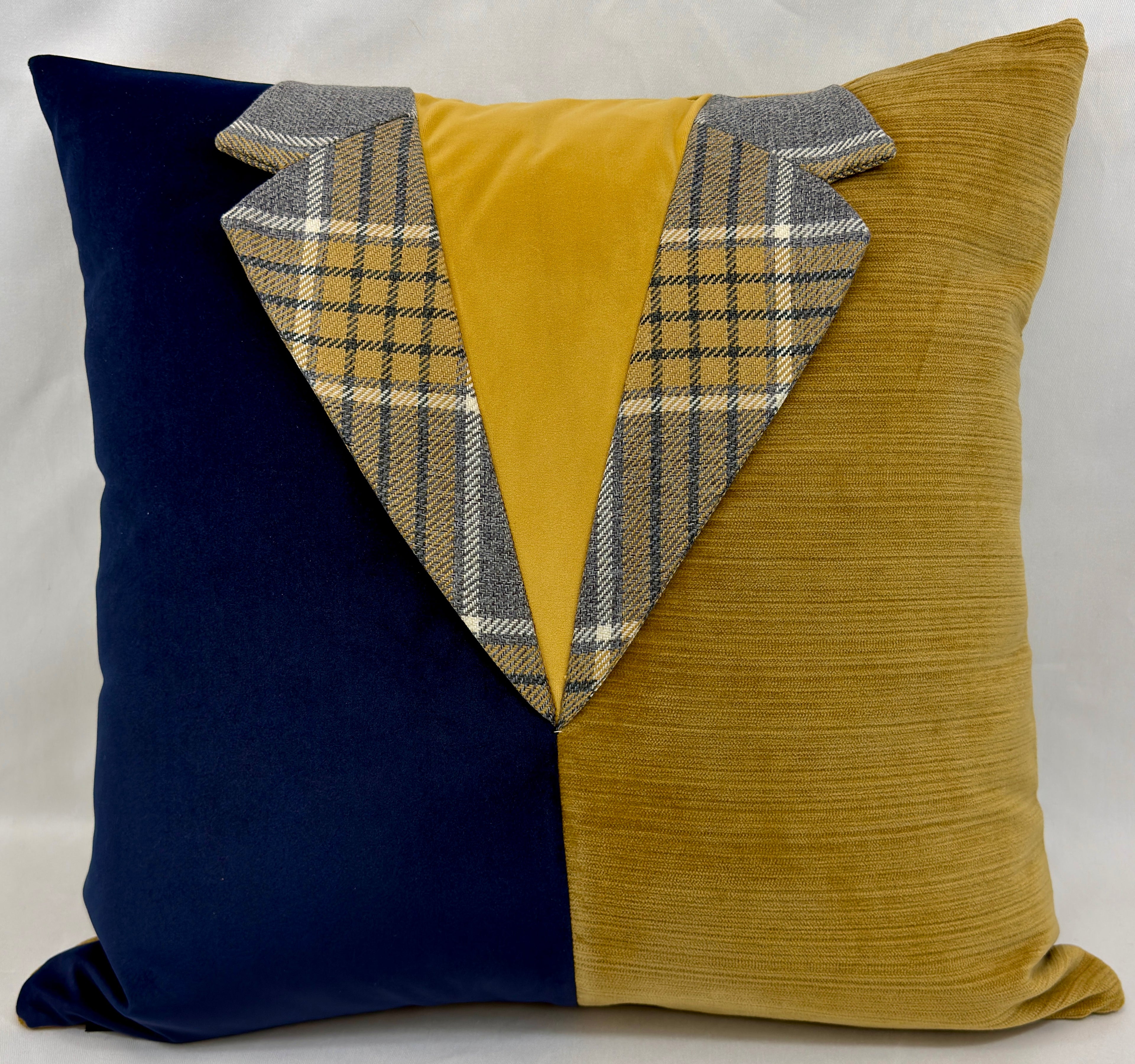 A square decorative throw pillow with a creative design resembling a suit jacket. The left half is navy blue velvet, the right half is mustard yellow corduroy, and the center V-shape is made of mustard yellow velvet and gray plaid tweed lapels.