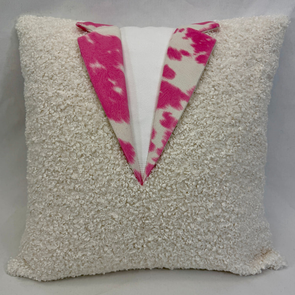 A square shaggy throw pillow in white with a V-shaped front panel featuring a white center and two bright pink lapels.