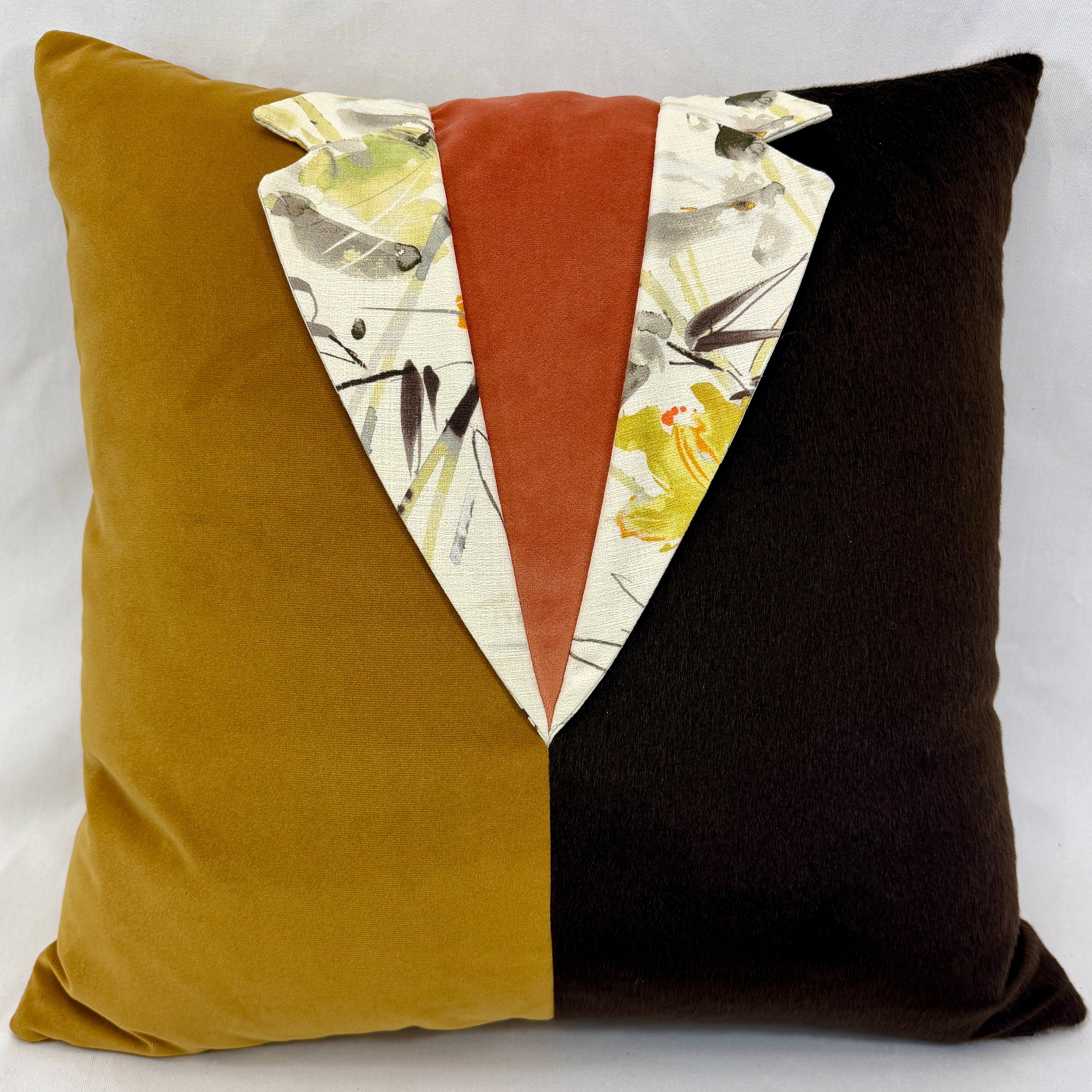 A square decorative throw pillow with a split velvet design: one half is mustard yellow, the other half is very dark brown, and the center features a vertical rust-orange panel flanked by white patterned fabric with brown  and yellow floral details.