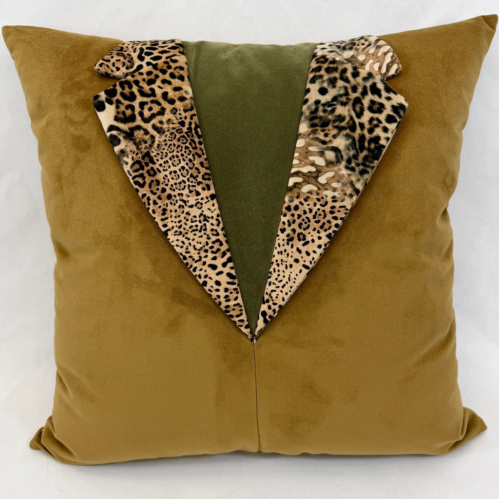 A square throw pillow in a textured mustard-yellow fabric, designed to look like a tuxedo jacket with a central olive green panel and leopard-print lapels.