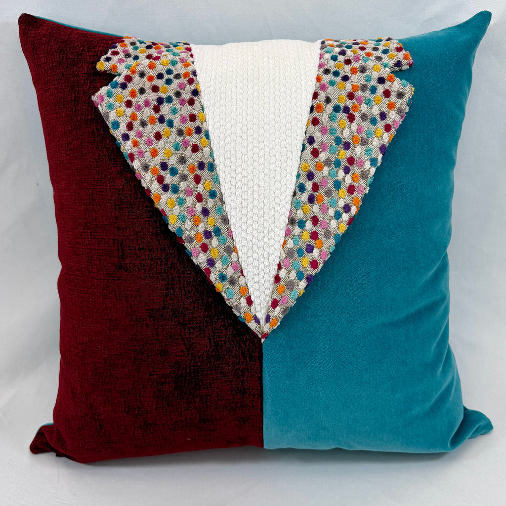 A square decorative throw pillow with a velvet split design in deep burgundy on the left and teal on the right, featuring a central white textured knit panel and a colorful embroidered polka-dot lapel detail.