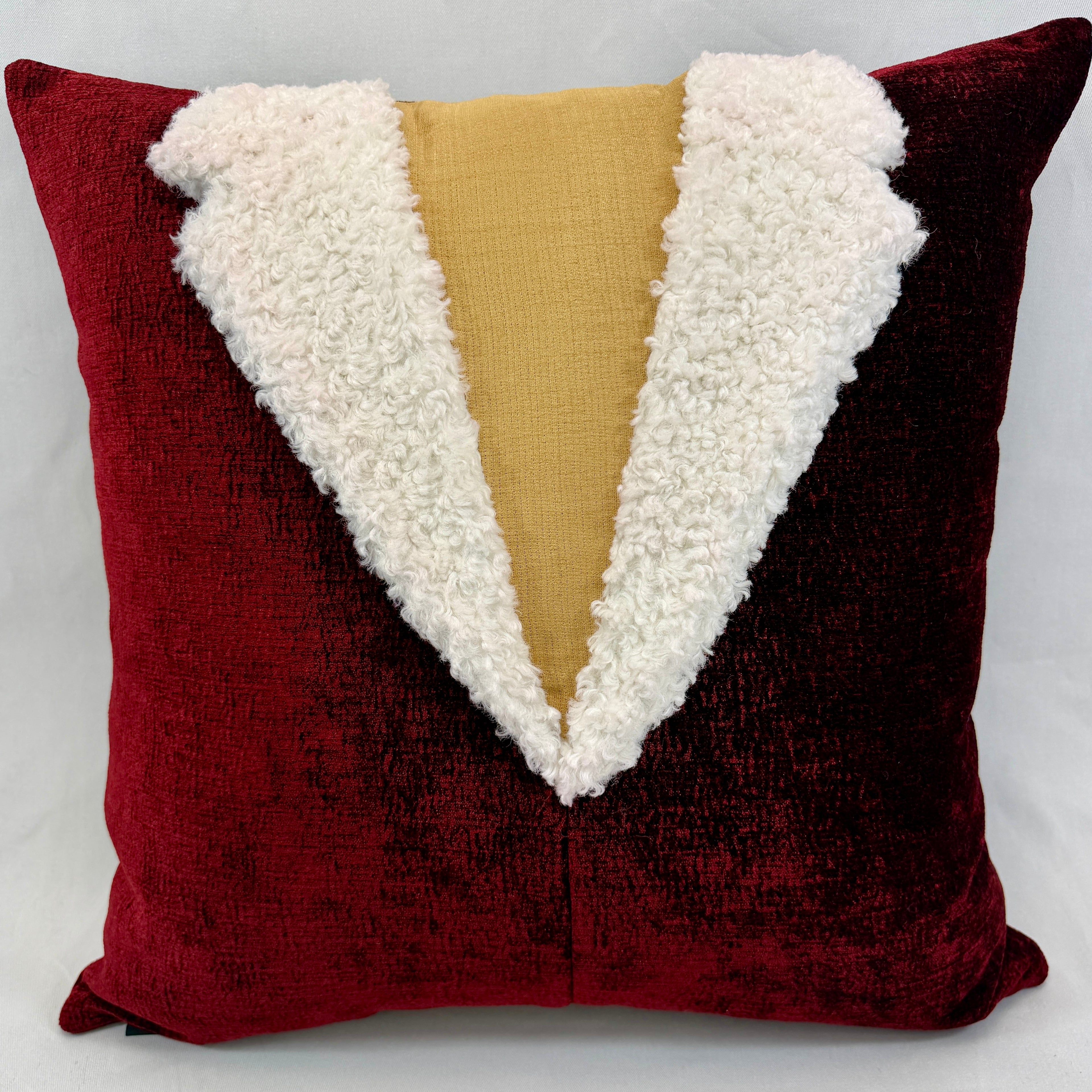 A square decorative throw pillow featuring a deep red velvet exterior with a plush white faux-fur collar and a central mustard yellow fabric panel, photographed against a light gray background.