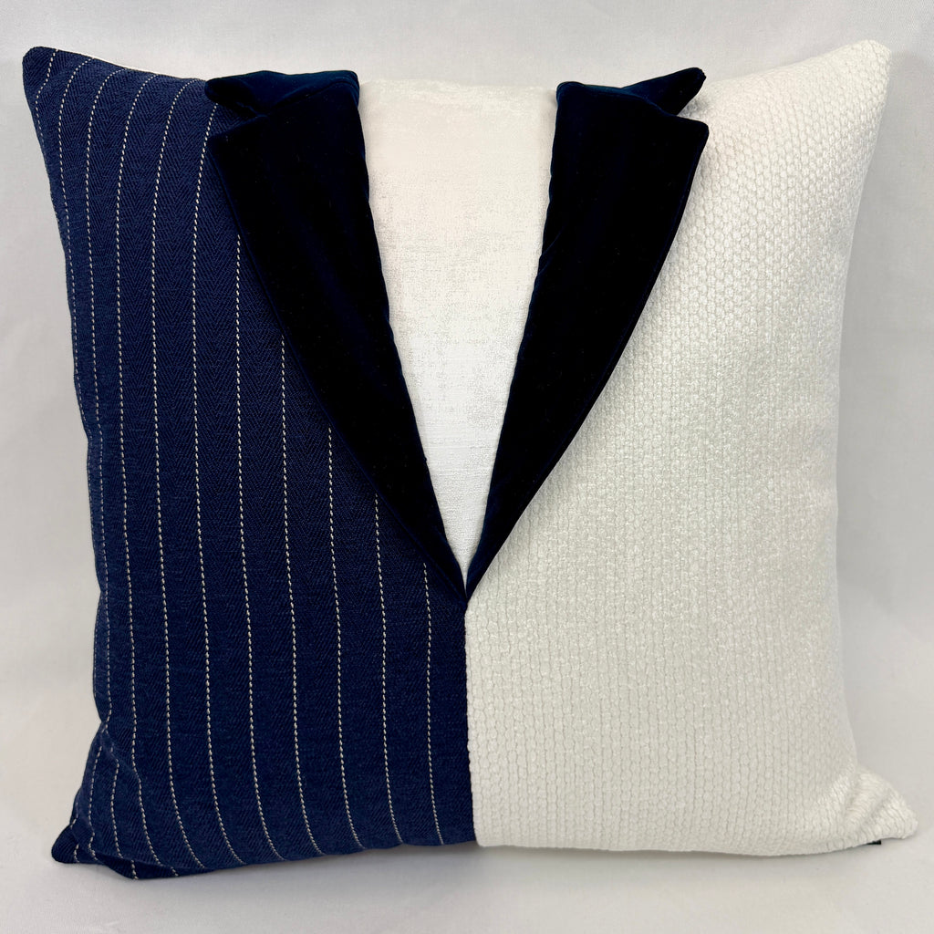 A square decorative throw pillow designed to look like a tuxedo jacket, featuring a navy blue pinstripe left side, a solid navy velvet collar, and a textured off-white textured fabric right side.