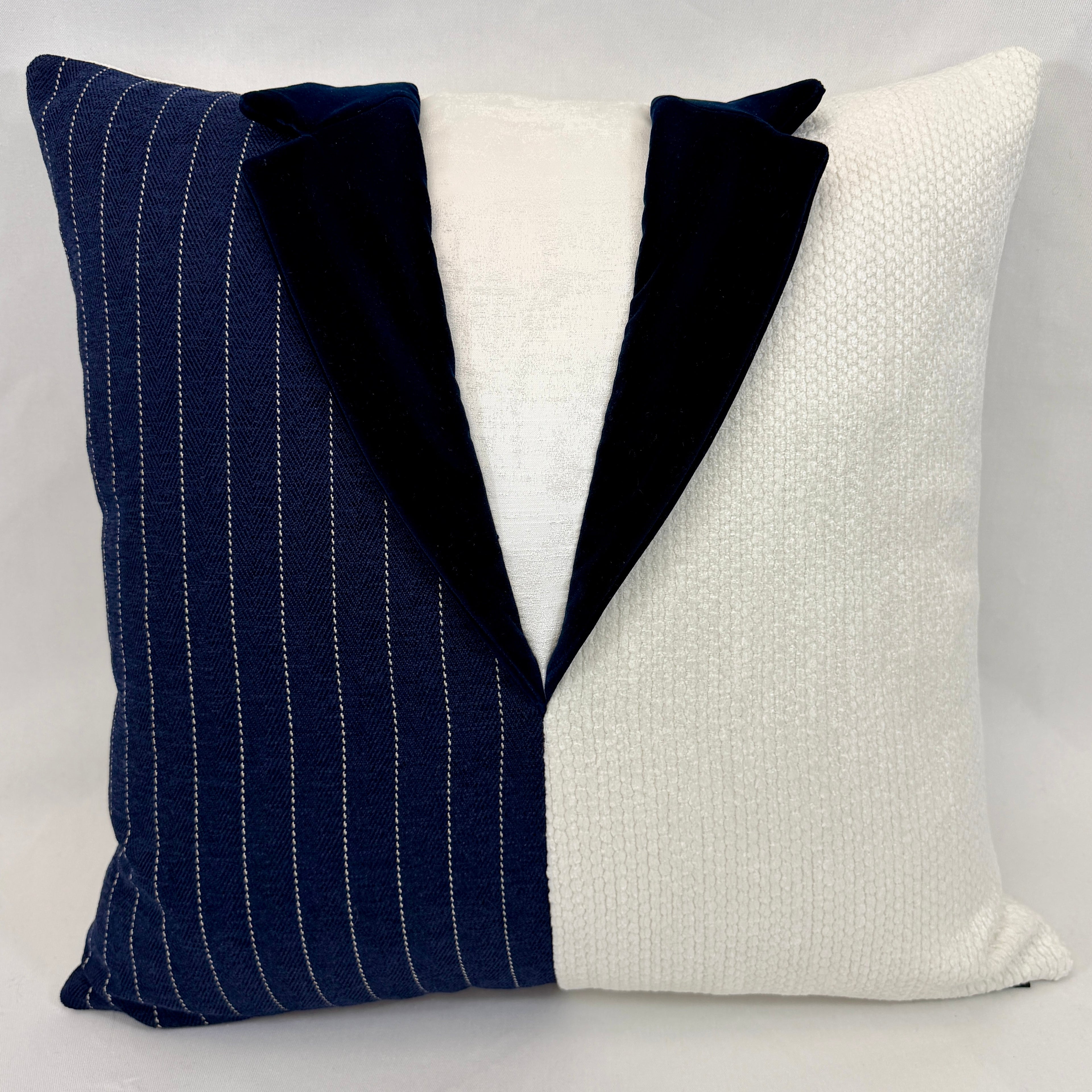 A square decorative throw pillow designed to look like a tuxedo jacket, featuring a navy blue pinstripe left side, a solid navy velvet collar, and a textured off-white textured fabric right side.