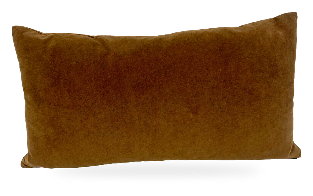 A rectangular lumbar throw pillow in a warm camel brown velvet fabric, photographed against a neutral white fabric backdrop.