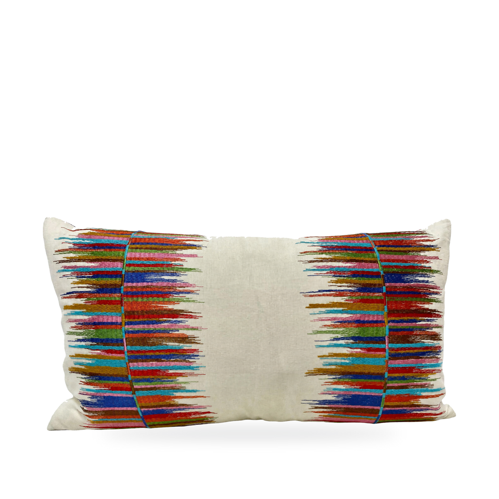 A rectangular lumbar throw pillow with a cream linen base and vibrant, multicolored embroidered ikat-style stripes on both sides, set against a plain white background.